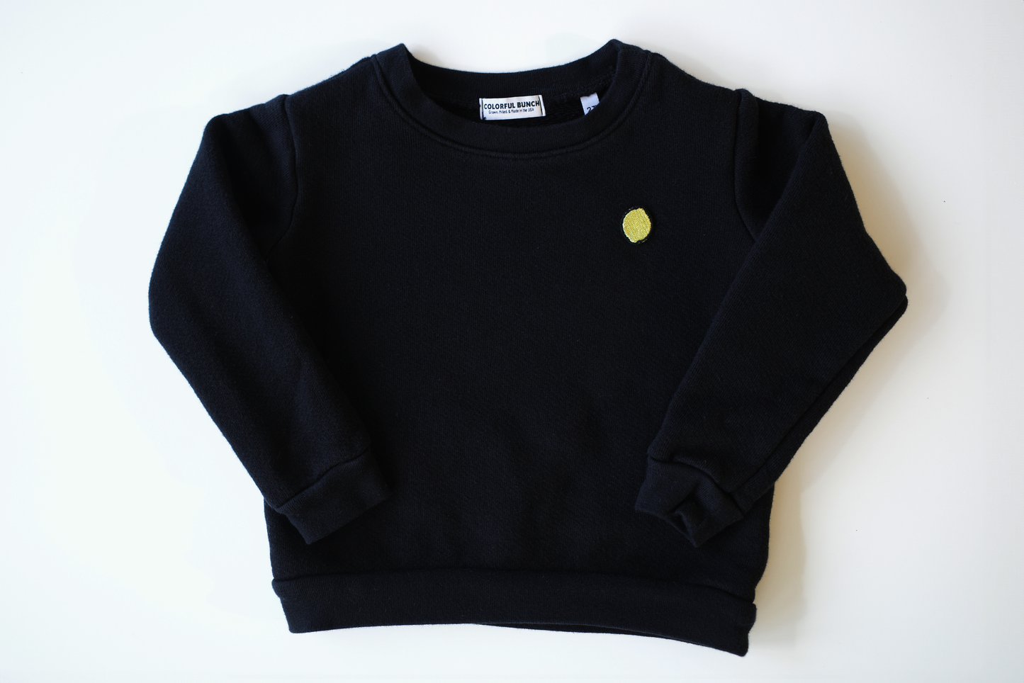 Vintage-inspired, garment-dyed black organic cotton children's sweatshirt with a vibrant lemon embroidery for a pop of color, made in the USA, part of Colorful Bunch's luxurious eco-friendly kids' clothing line.
