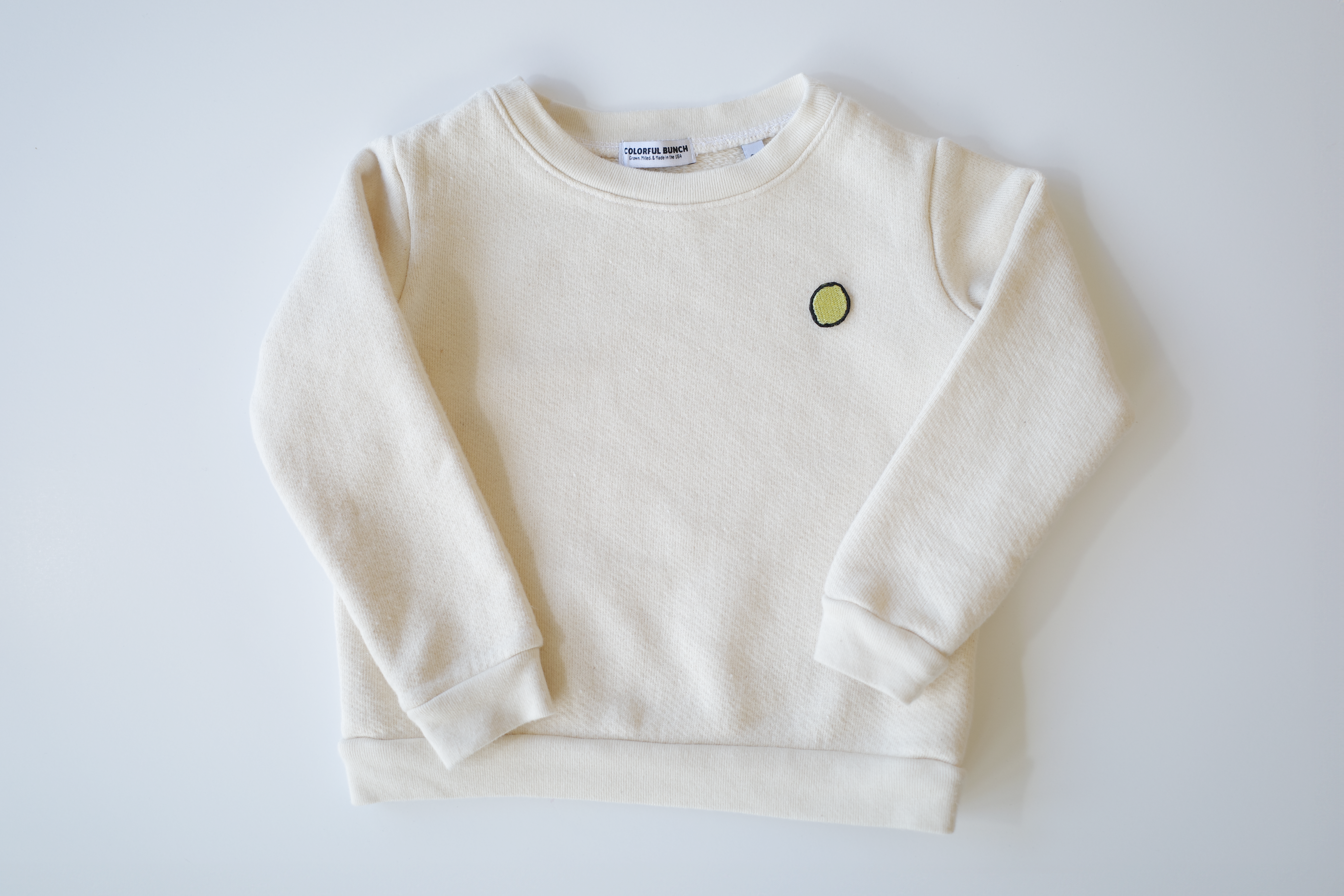 Organically sourced, uncolored toddler's pullover with a delicate, eco-friendly embroidered lime motif, proudly made in the USA, from Colorful Bunch's sustainable kids' apparel line.