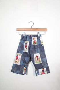 Kids’ pull-on pants in country patchwork, shown hanging from a wooden hanger.