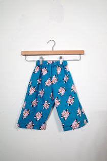 Kids’ pull-on pants in little piggies, shown hanging from a wooden hanger.