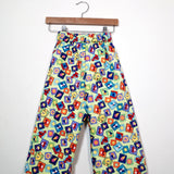 Kids’ pull-on pants in playtime tiles, shown hanging from a wooden hanger.